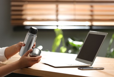 Photo of Woman with modern thermos at workplace, closeup