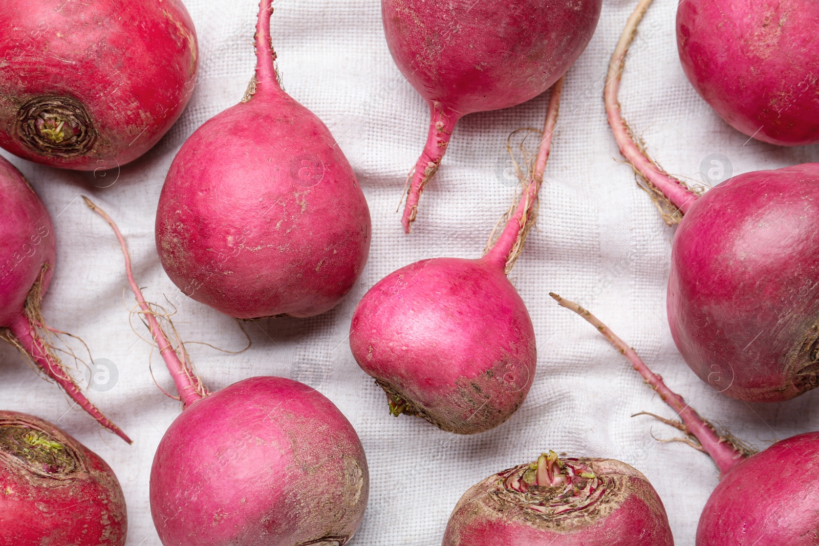 Photo of Red turnips on white fabric, flat lay