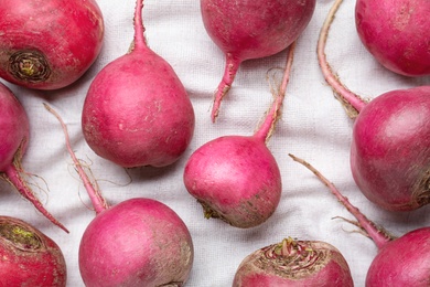 Photo of Red turnips on white fabric, flat lay