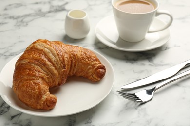 Photo of Delicious fresh croissant served with coffee on light marble table