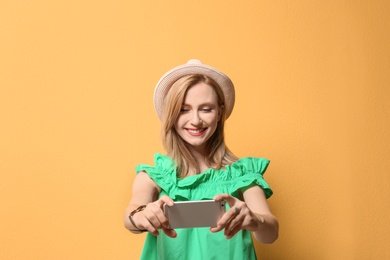 Photo of Attractive young woman taking selfie on color background