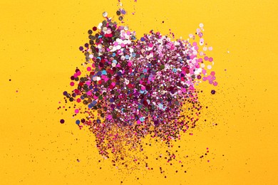 Photo of Shiny bright glitter on yellow background, flat lay