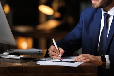 Photo of Young businessman working in office alone at night, closeup