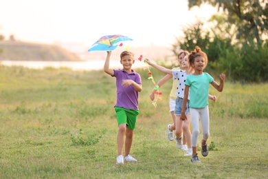 Cute little children playing with kite outdoors