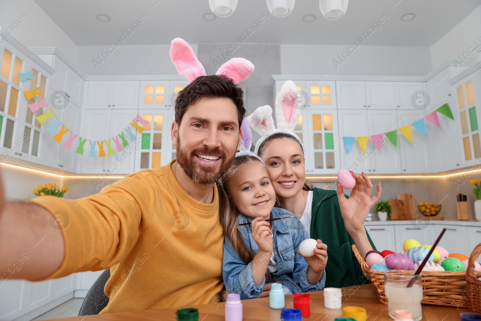 Photo of Happy family making selfie while painting Easter eggs in kitchen