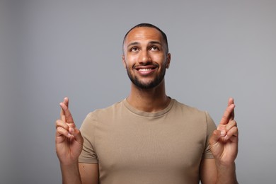 Photo of Happy man crossing his fingers on grey background