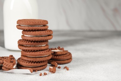 Photo of Tasty chocolate sandwich cookies with cream on light grey table, space for text