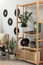 Photo of Living room interior with stylish turntable on wooden shelving unit and vinyl records