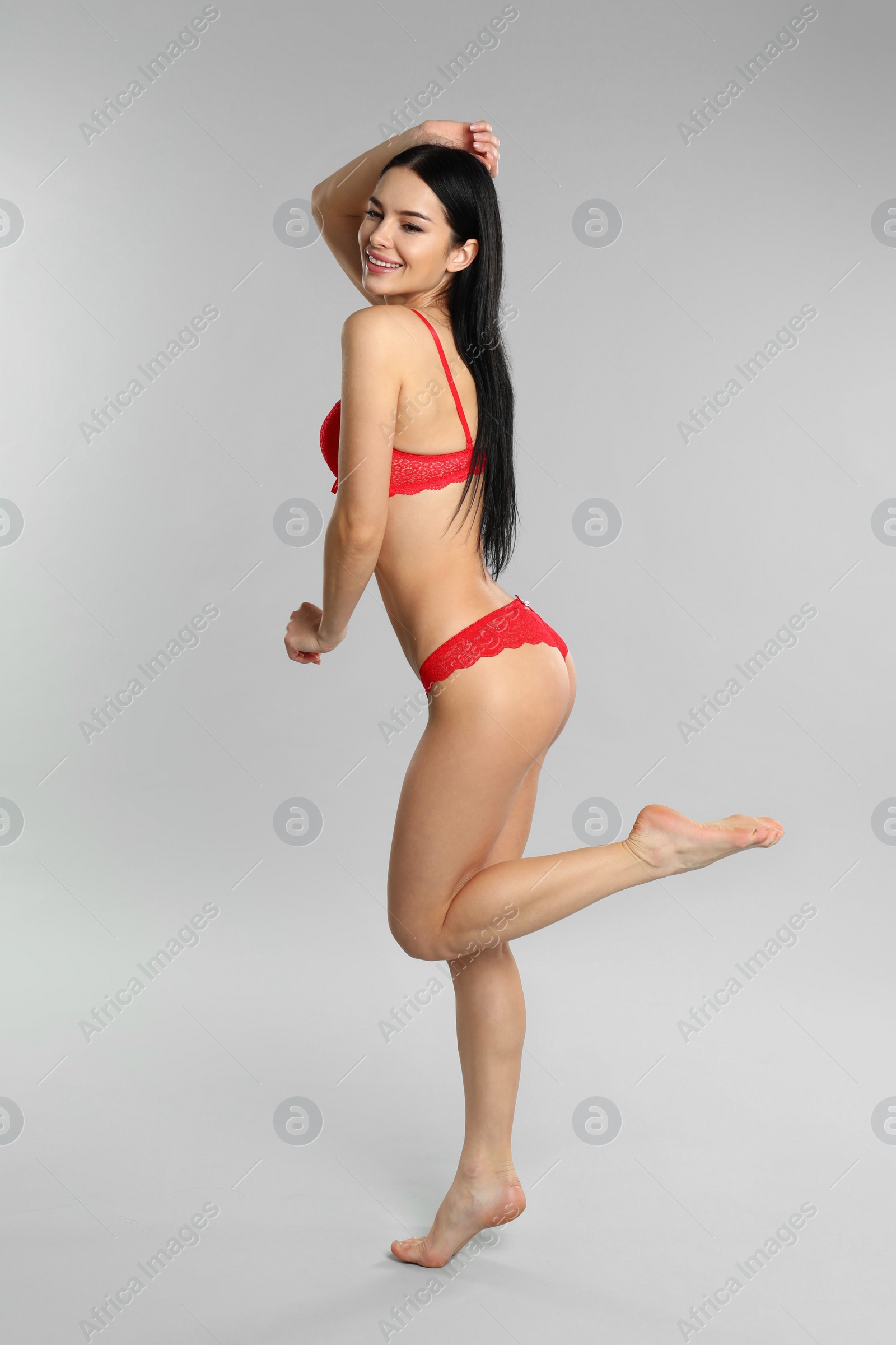 Photo of Beautiful young woman in red underwear on grey background