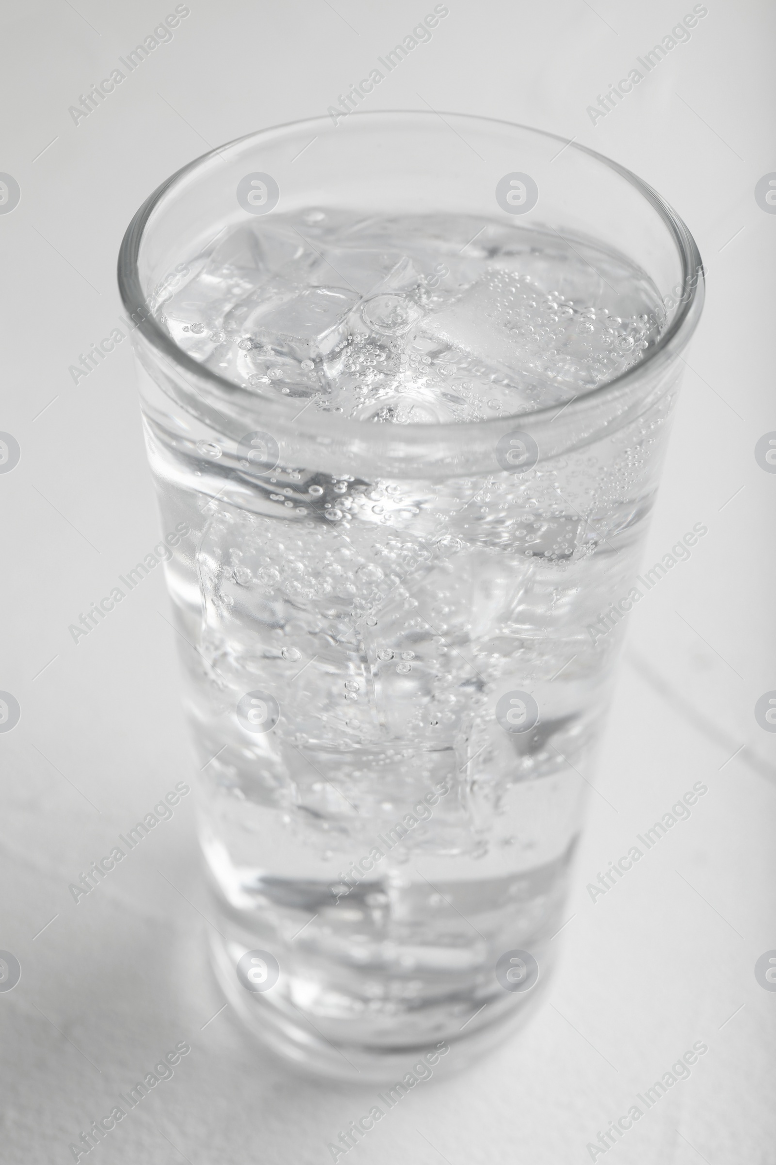 Photo of Glass of soda water on white table, closeup