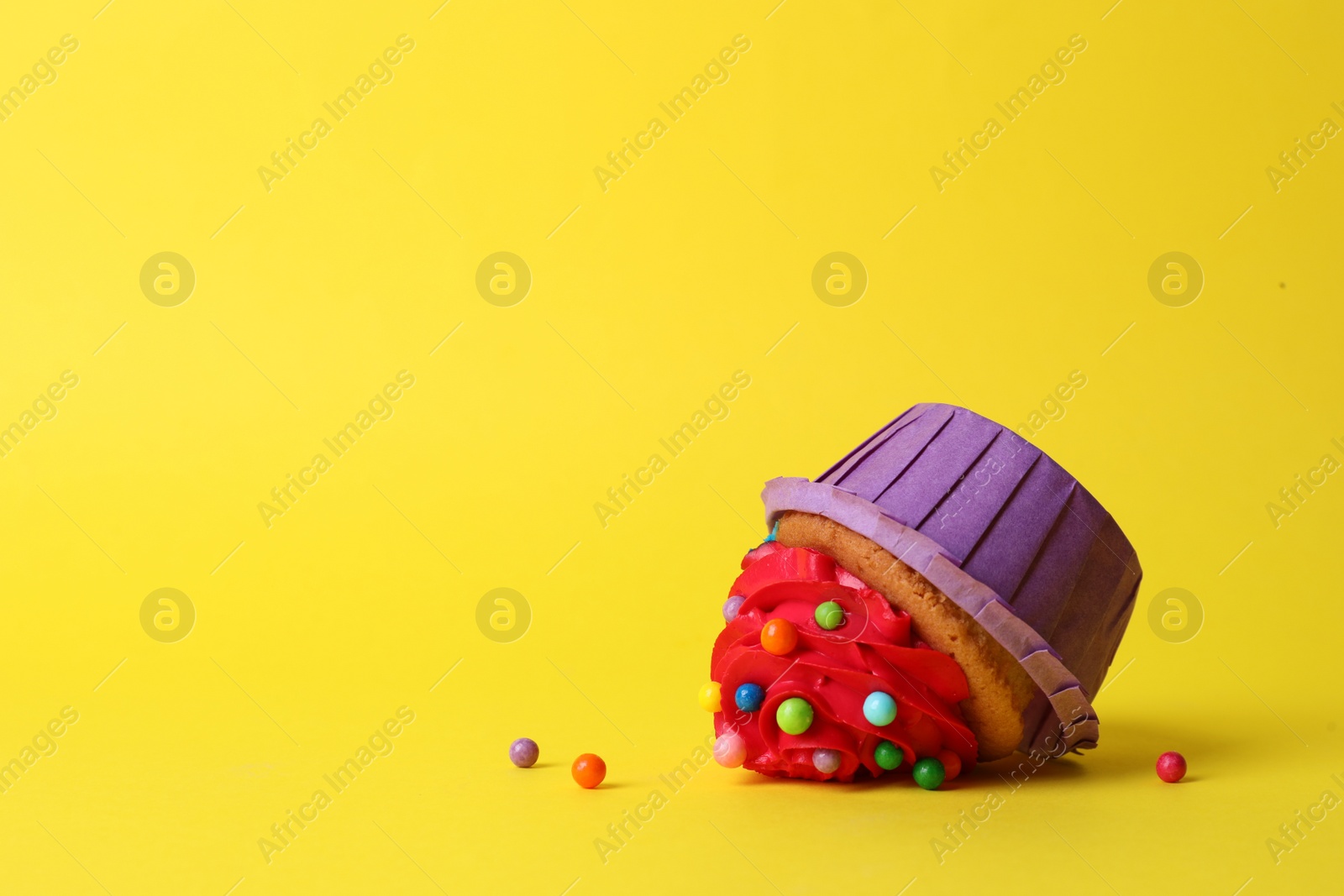 Photo of Dropped cupcake with cream on yellow background. Troubles happen