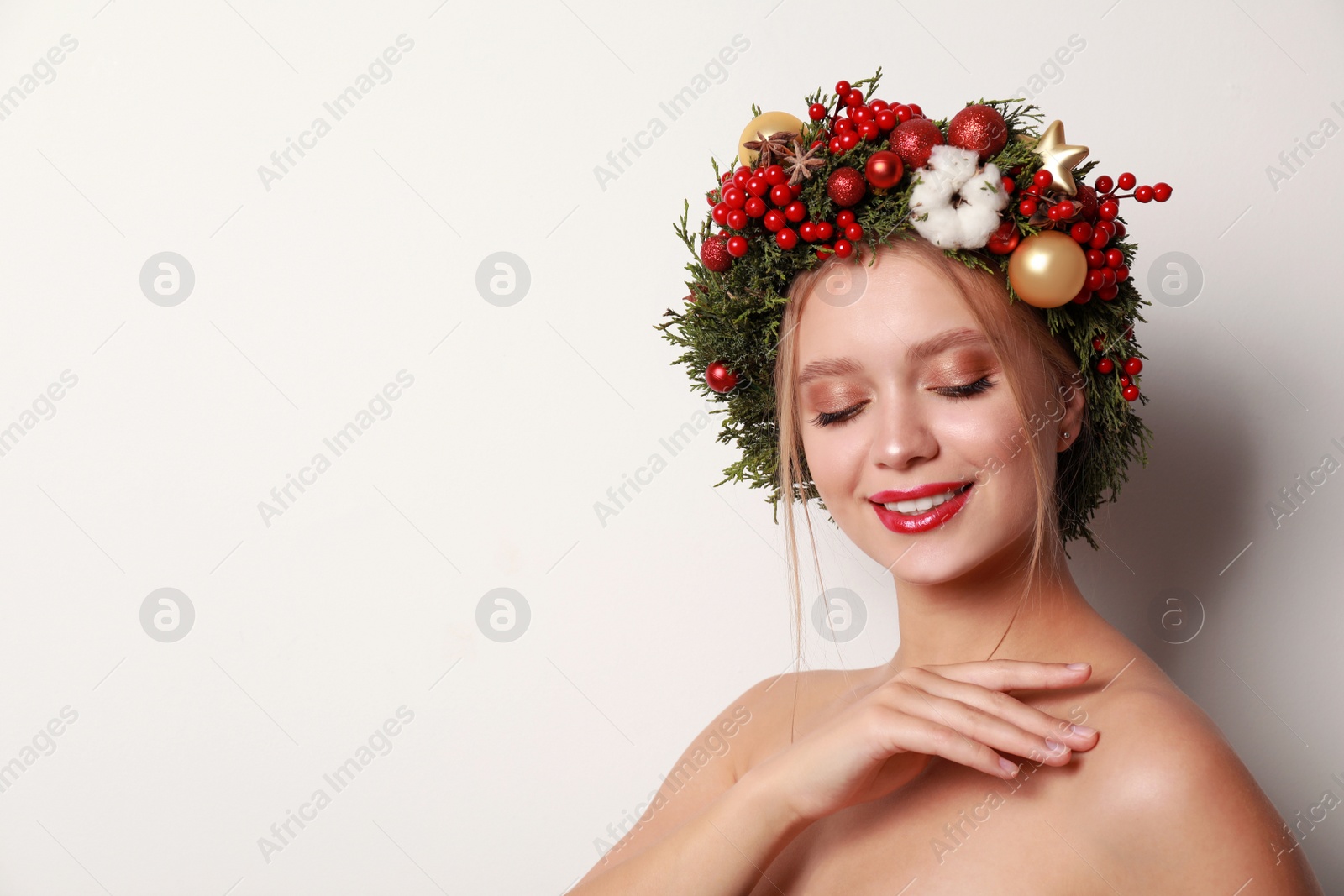 Photo of Beautiful young woman wearing Christmas wreath on white background. Space for text