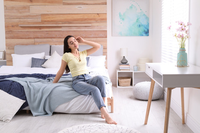 Photo of Woman sitting on bed in modern room. Elegant interior