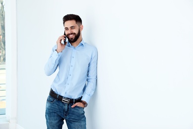Photo of Handsome young man talking with client by phone at work. Space for text