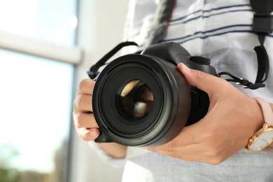 Photo of Female photographer with professional camera on blurred background, closeup