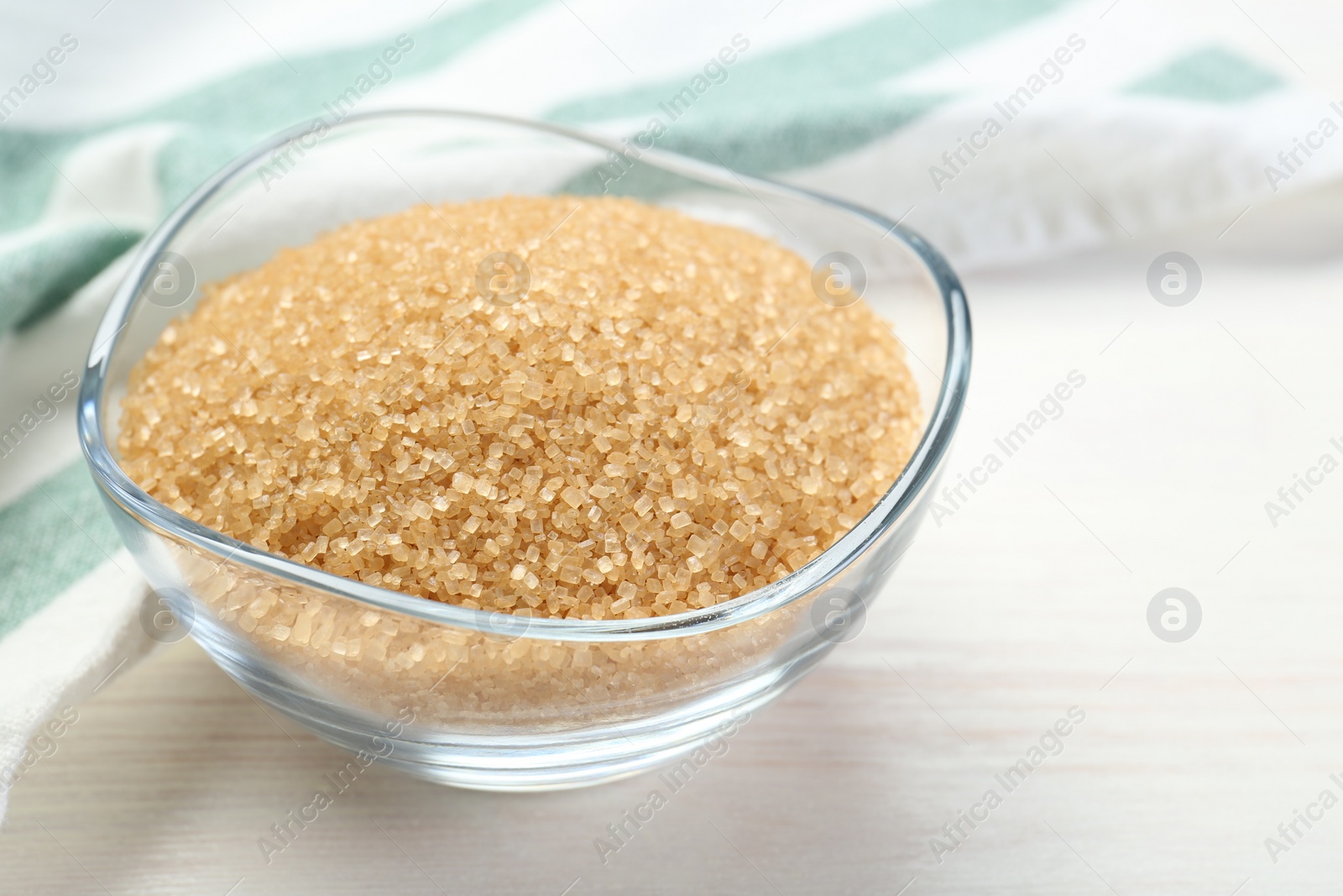 Photo of Brown sugar in glass bowl on white wooden table, closeup