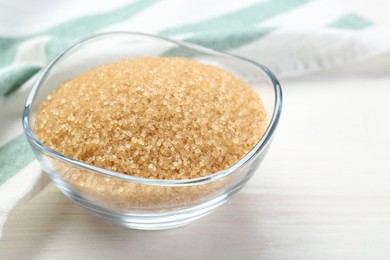 Photo of Brown sugar in glass bowl on white wooden table, closeup