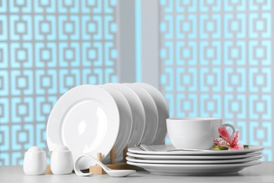 Set of clean dishware with flowers on light grey table