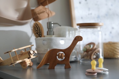 Photo of Wooden toys and pacifiers on grey table in child room