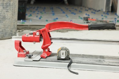 Photo of Tile cutter and tools on floor indoors, closeup