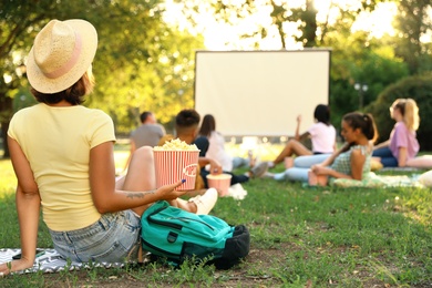 Photo of Young woman with popcorn watching movie in open air cinema. Space for text