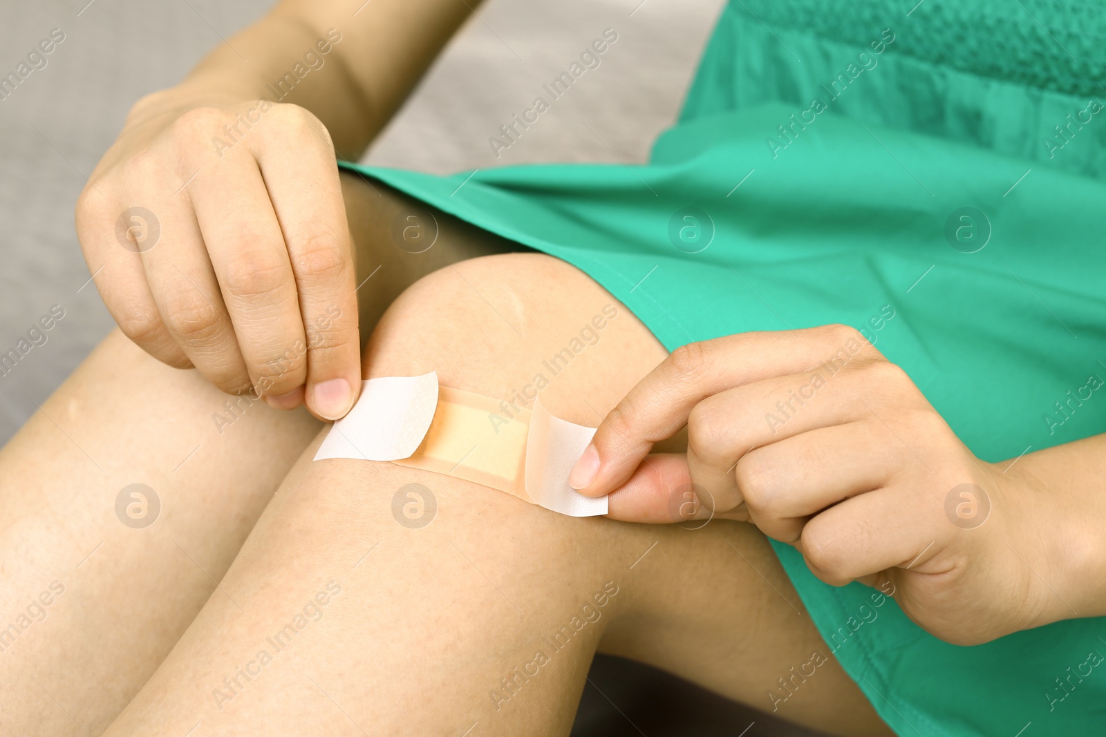 Photo of Woman applying plaster on knee, closeup view