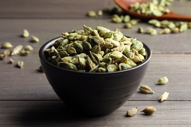 Bowl of dry cardamom pods on wooden table