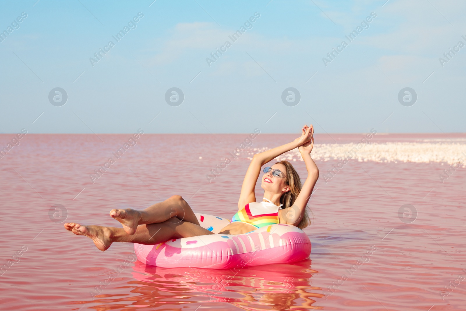 Photo of Beautiful woman on inflatable ring in pink lake