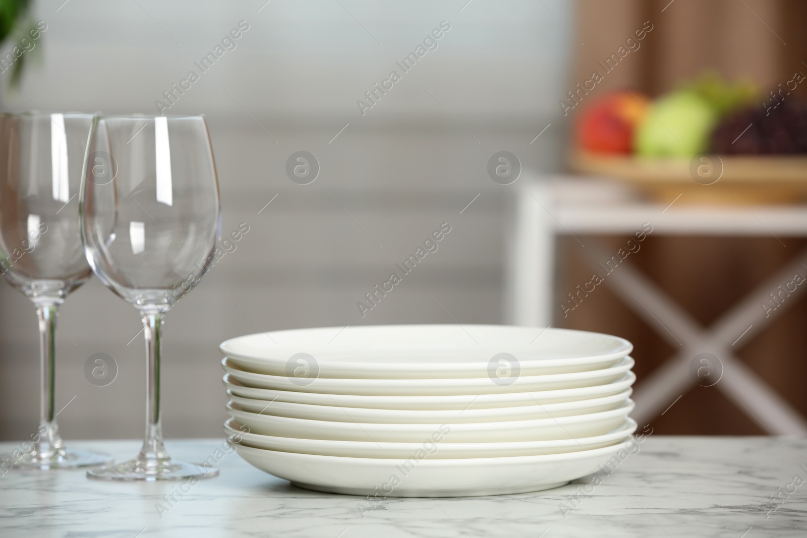 Photo of Stack of plates and glasses on white marble table indoors