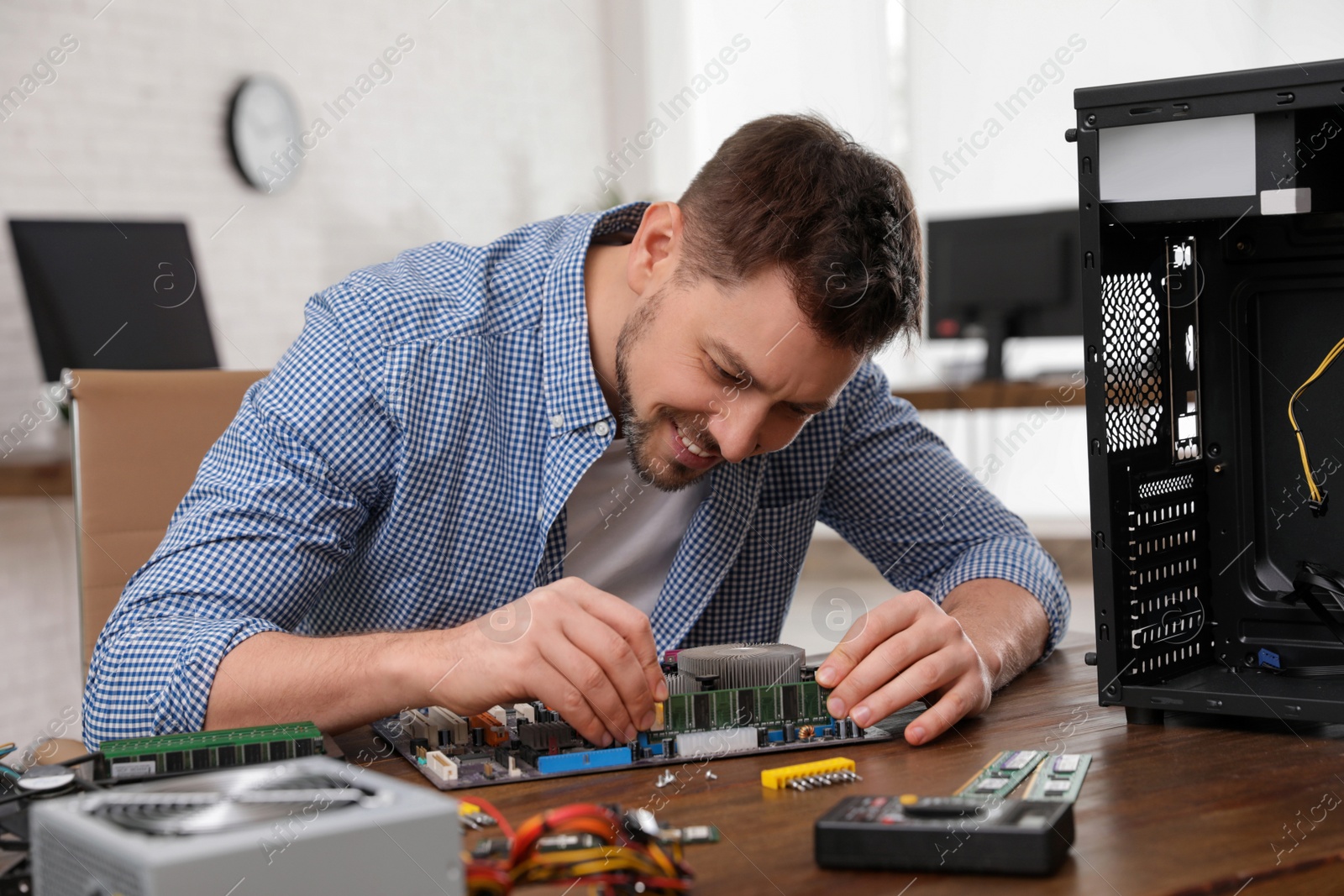 Photo of Male technician repairing motherboard at table indoors