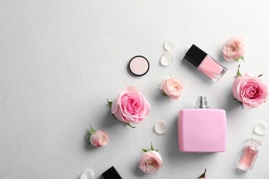 Photo of Flat lay composition with bottles of perfume, cosmetics and roses on grey background. Space for text
