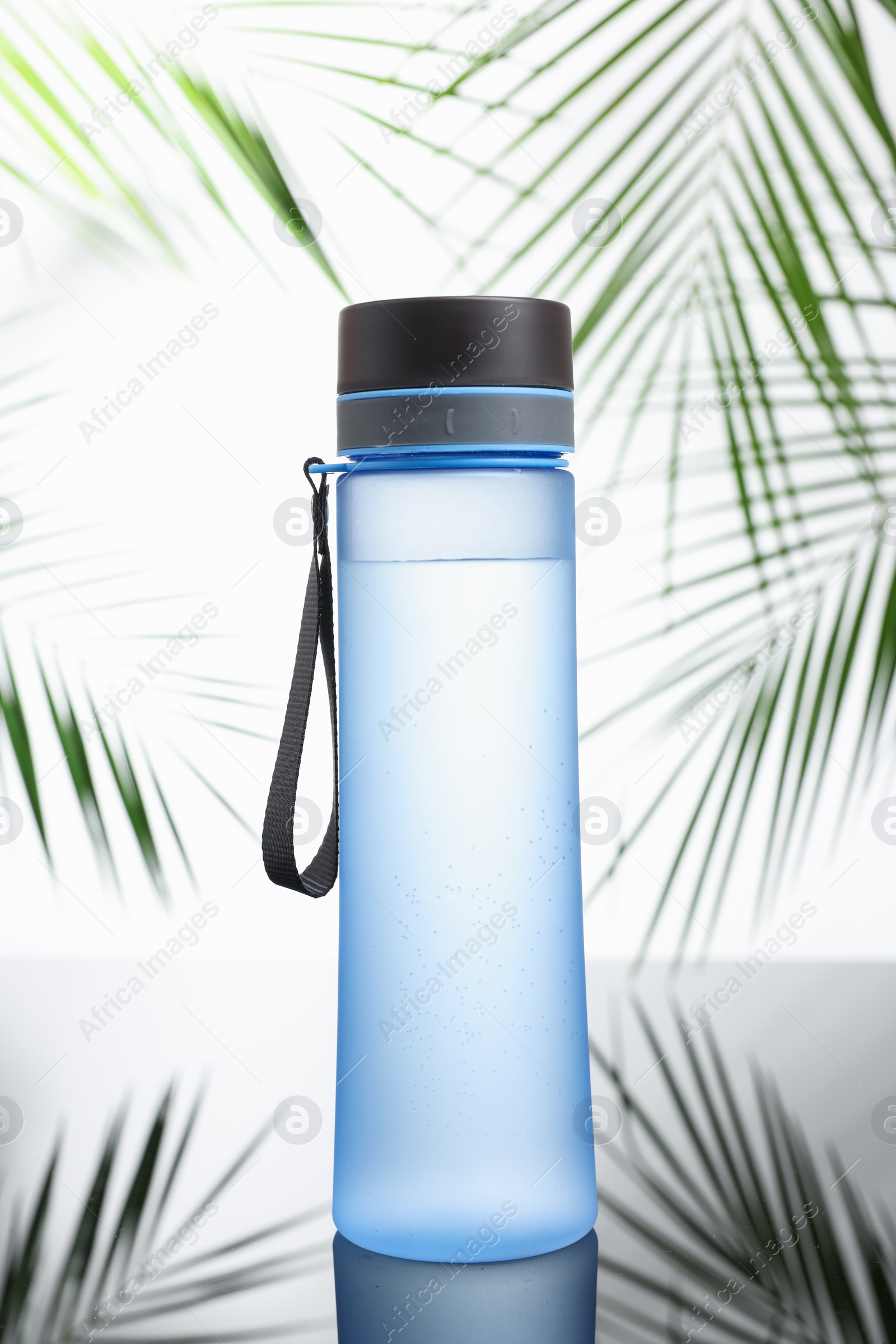 Photo of Stylish thermo bottle on mirror table against white background