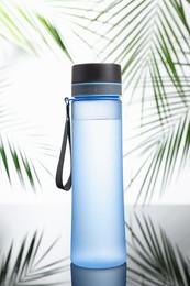 Photo of Stylish thermo bottle on mirror table against white background