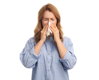 Woman with tissue suffering from runny nose on white background