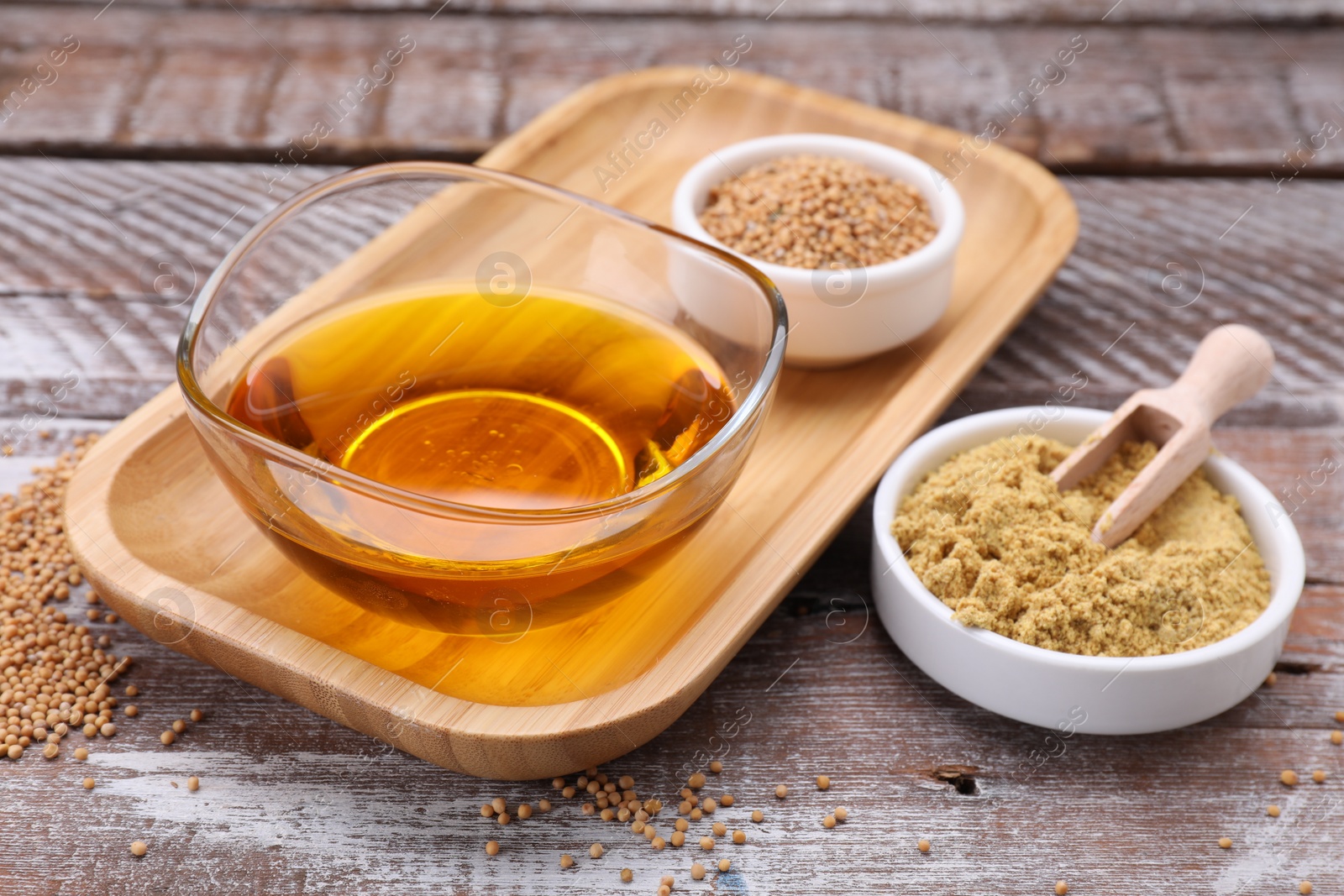Bowl of natural oil, mustard seeds and powder on wooden table, closeup Photo of Bowl of natural oil, mustard seeds and powder on wooden table, closeup