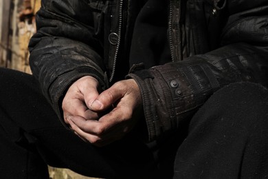 Poor homeless man with dirty hands outdoors, closeup