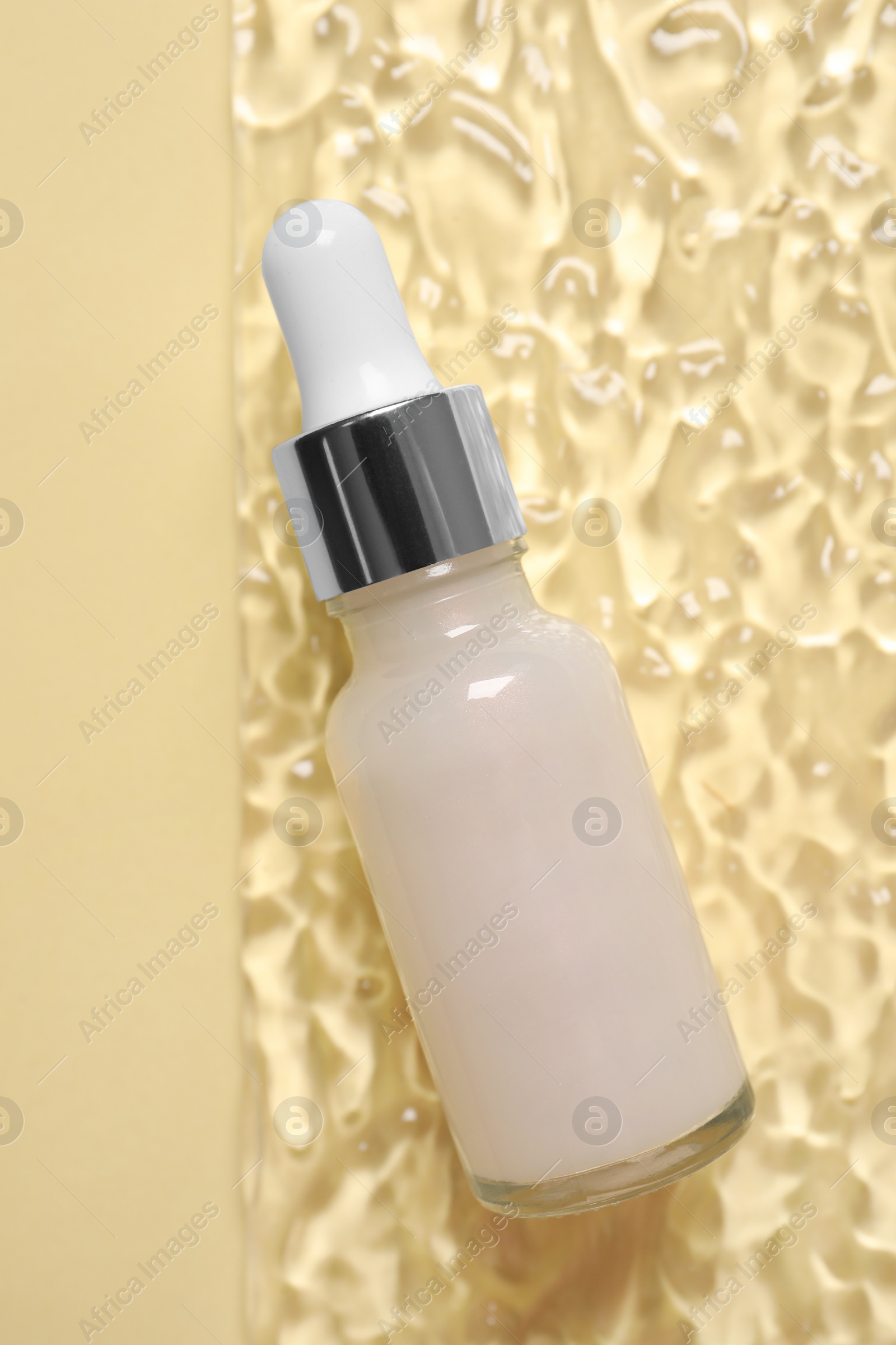 Photo of Bottle of cosmetic serum on beige background, top view