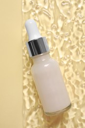 Photo of Bottle of cosmetic serum on beige background, top view