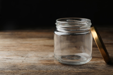 Photo of Empty glass jar on wooden table, space for text