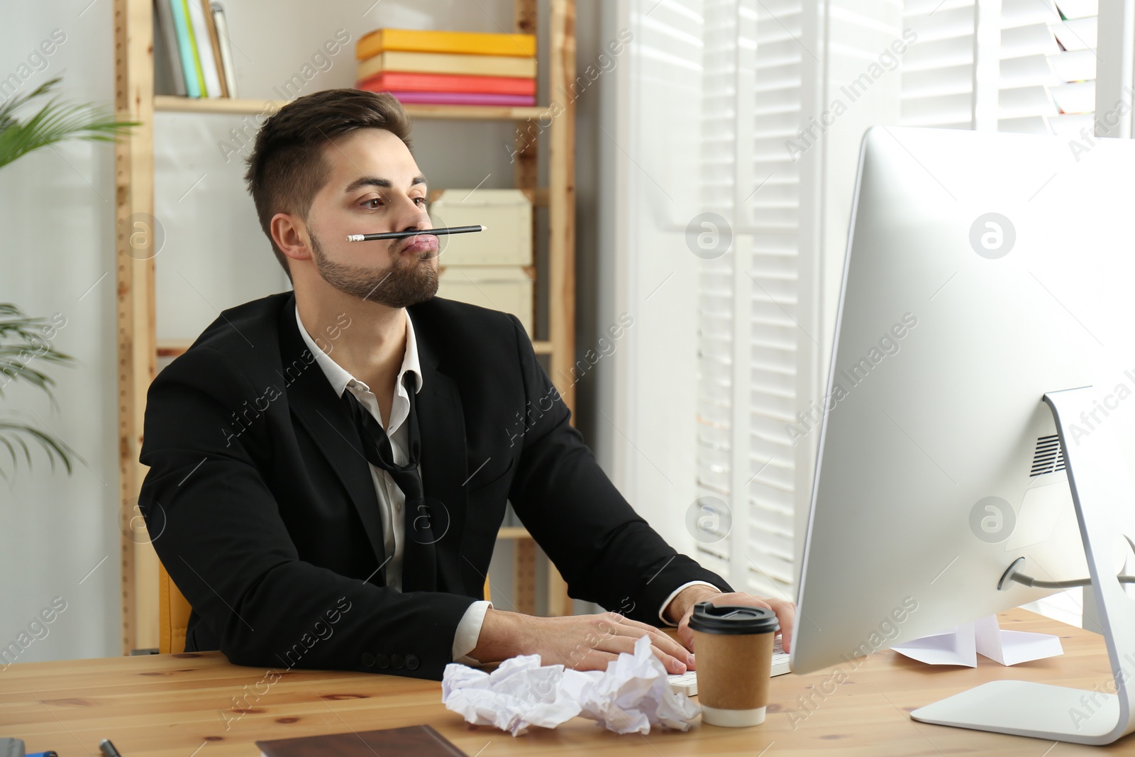 Photo of Lazy employee playing with pencil at table in office