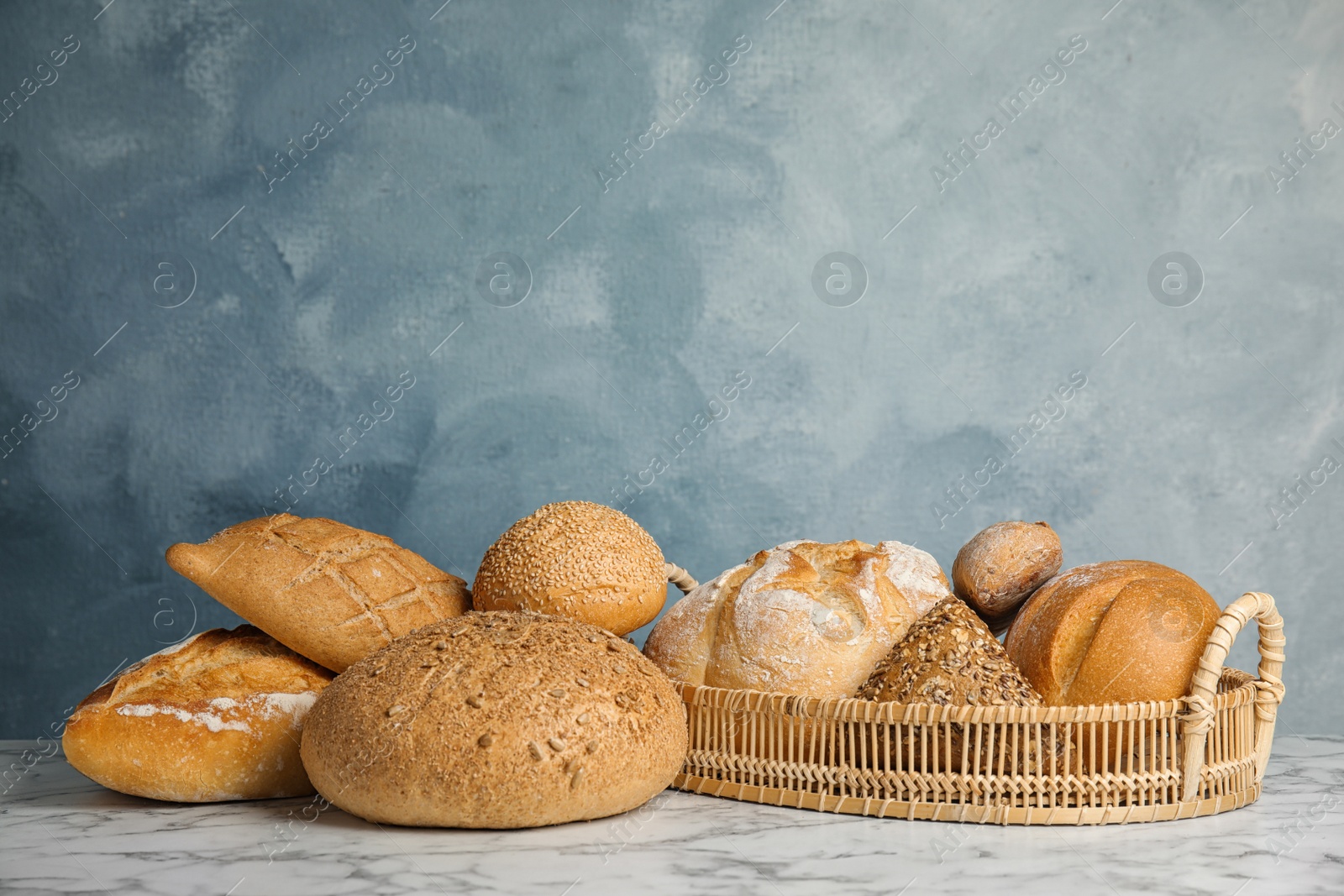 Photo of Loaves of different breads on white marble table