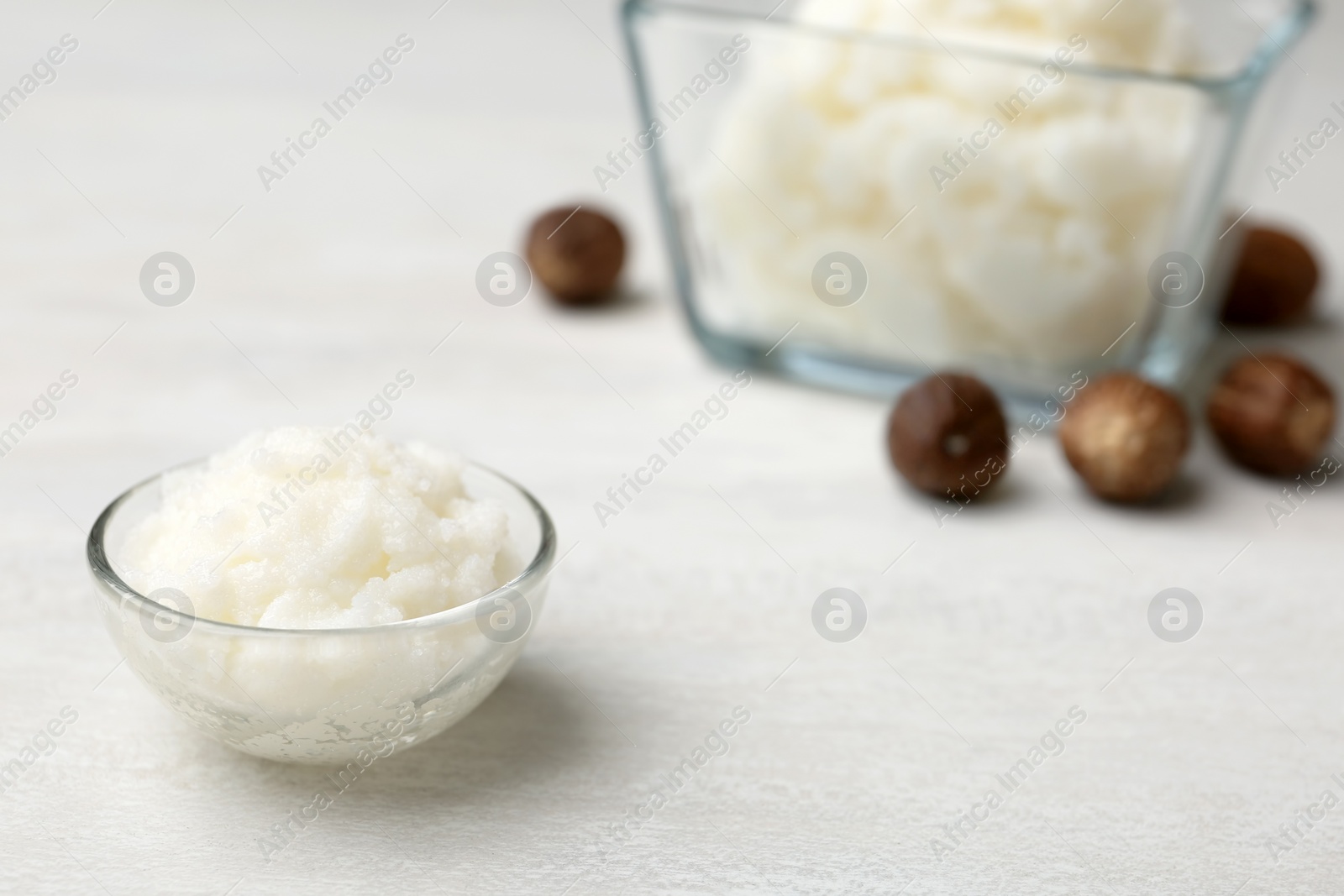 Photo of Shea butter in bowl and nuts on table