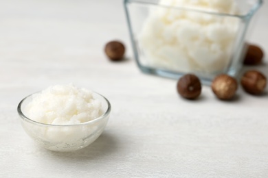 Shea butter in bowl and nuts on table