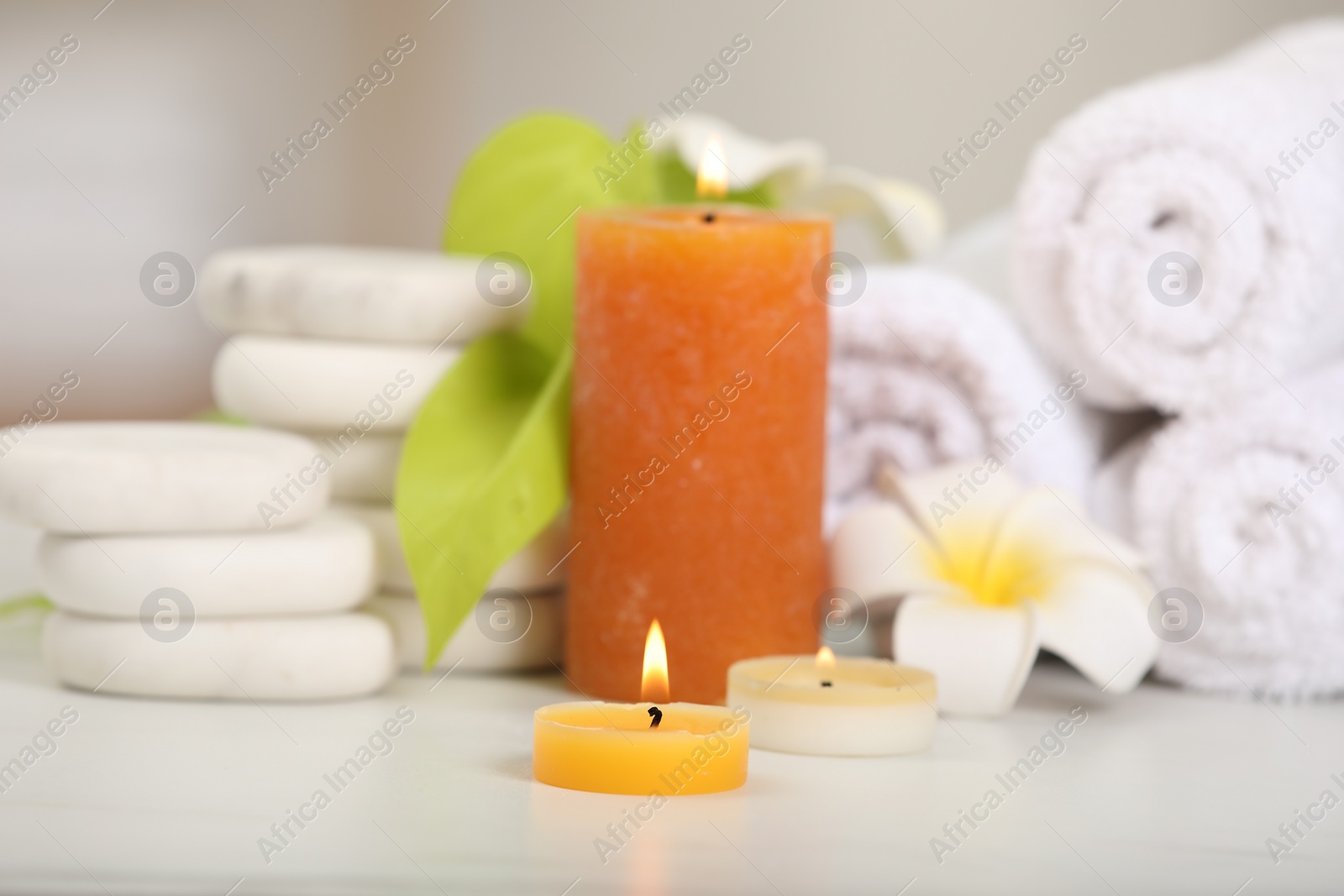 Photo of Composition with different spa products and burning candles on white table, closeup