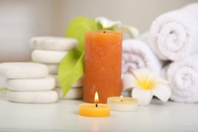 Composition with different spa products and burning candles on white table, closeup