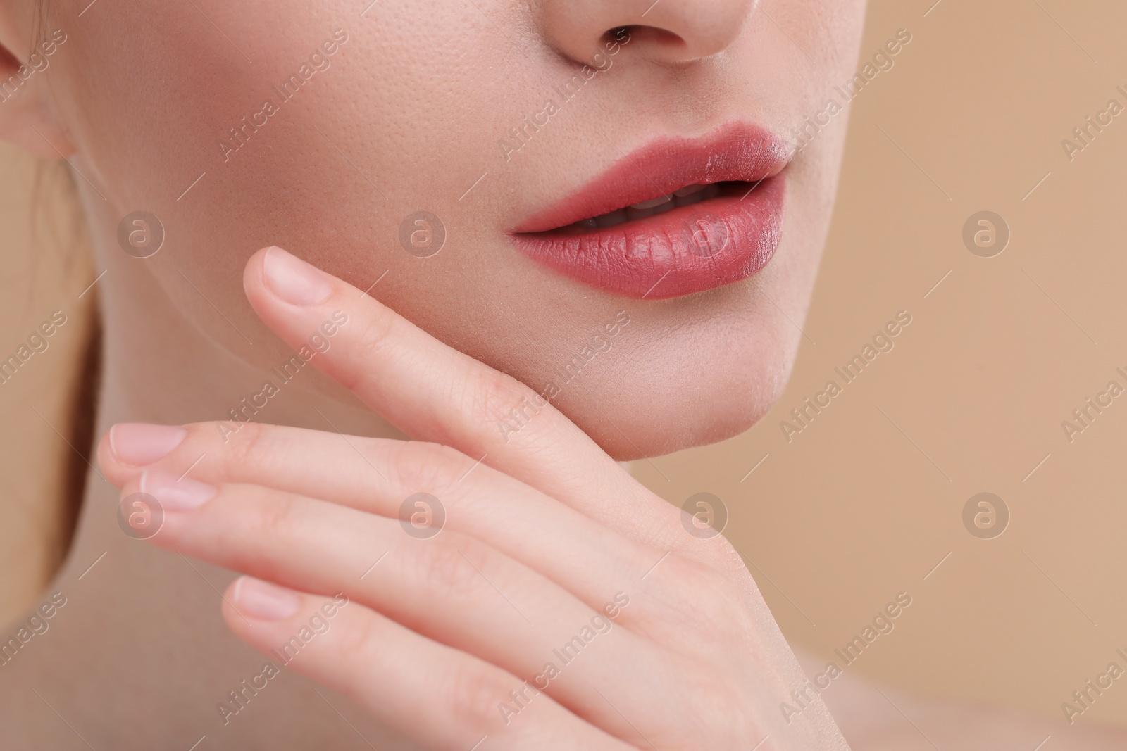 Photo of Young woman with beautiful full lips on beige background, closeup