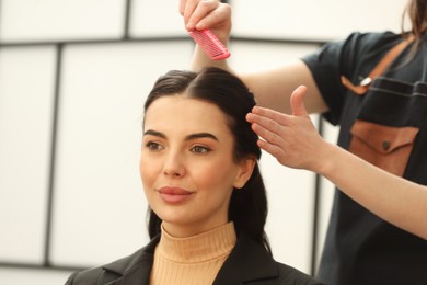 Hair styling. Professional hairdresser combing woman's hair indoors, closeup