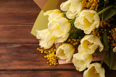 Photo of Bouquet with beautiful tulips and mimosa flowers on wooden table. Space for text