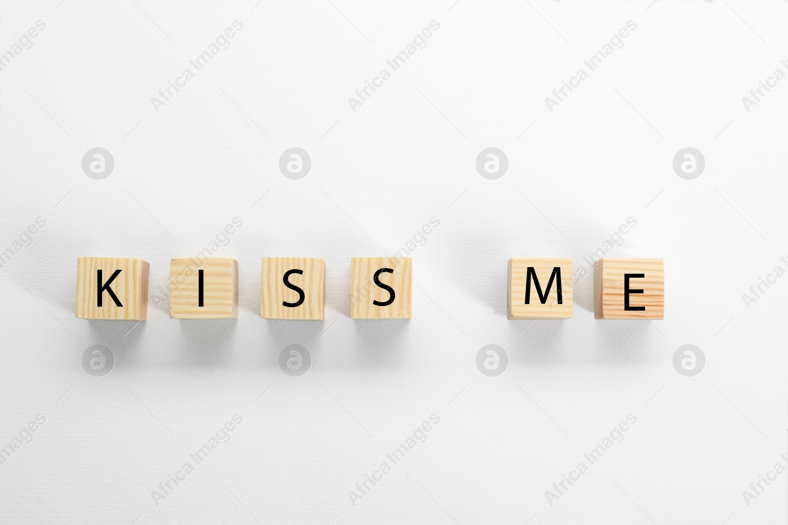 Photo of Wooden cubes with phrase Kiss Me on white background, flat lay