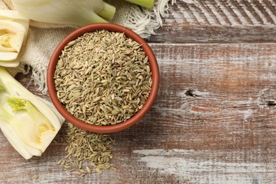 Photo of Fennel seeds and fresh stalks on wooden table, flat lay. Space for text